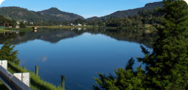 a body of water with trees and mountains in the background