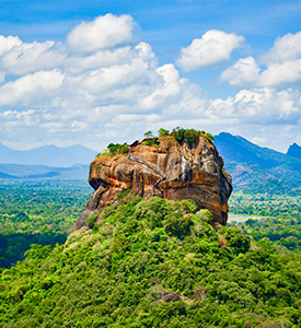 a large rock formation in a forest with Sigiriya in the background
